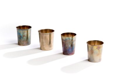 quatre tasses en métal sont alignées les unes à côté des autres sur une surface blanche