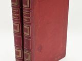 two red books sitting on top of each other on a white surface