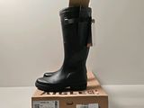 des bottes en caoutchouc noires posées sur une boîte en carton, sur une surface blanche