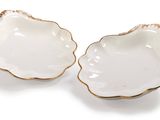 two white and gold shell shaped dishes on a white surface