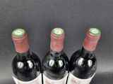 three bottles of wine are lined up in a row on a table