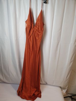une robe orange suspendue à un cintre devant un fond blanc