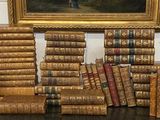 de nombreux livres posés sur une table, avec un tableau en arrière-plan