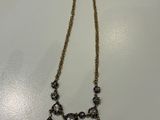 a gold necklace with black and white stones on a white surface