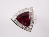 un gros plan d'une bague sertie d'une pierre rouge et de diamants