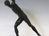 statue en bronze représentant un homme dans une pose, posée sur un socle en marbre