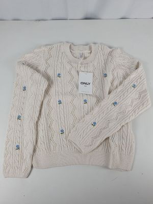 cream cable knit sweater with blue buttons and a tag on the chest