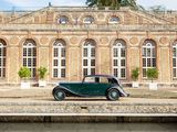 a green car parked in front of a large brick building
