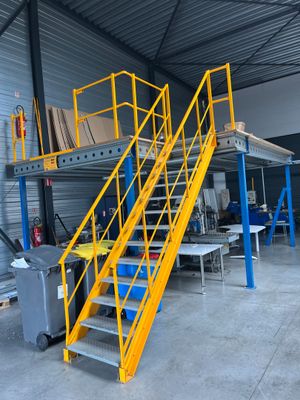 a yellow staircase in a warehouse next to some tables and chairs