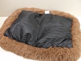 a brown dog bed with a black blanket on it