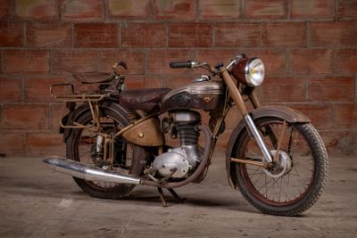 a old motorcycle that is parked in front of a brick wall