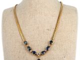 un collier en or orné de pierres bleues et de perles, posé sur un mannequin