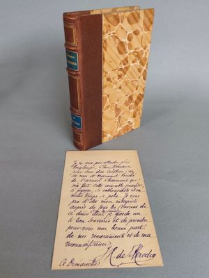 un vieux livre posé sur une table à côté d'une feuille de papier