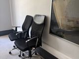 a black office chair sitting in front of a large painting