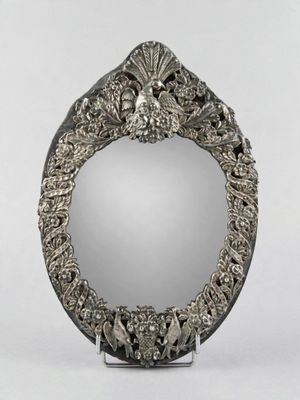 un miroir en argent richement décoré, posé sur un pied et orné d'un motif floral