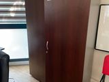 a red chair sitting in front of a wooden cabinet