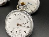 three different types of pocket watches on a black surface
