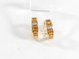 une paire de boucles d'oreilles en or jaune et diamants posées sur une surface transparente
