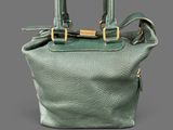 a close up of a green handbag on a gray background