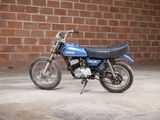 a small blue motorcycle parked in front of a brick wall