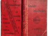 an old red book sitting on top of a table next to another book