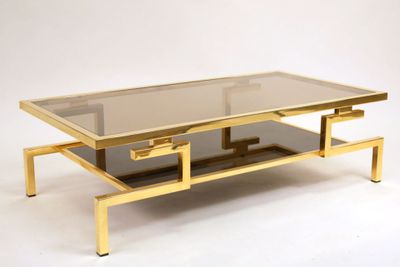 a gold coffee table with a glass top on a white background
