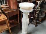 a white pedestal with a candle on top of it