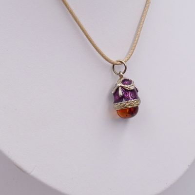 collier orné d'une perle en verre violette et orange sur un mannequin blanc