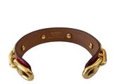 a close up of a brown leather bracelet with gold hardware
