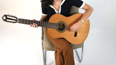 une femme assise sur une chaise, tenant une guitare