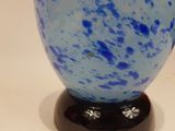 a blue glass vase sitting on top of a black stand
