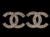 a pair of chanel earrings on a black background