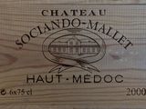 une caisse en bois sur laquelle est accrochée une pancarte indiquant « Château Soccando Mallet Haut-Médoc »