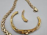 an image of a gold necklace and bracelet on a gray surface