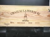 une caisse en bois sur laquelle est accrochée une pancarte indiquant « Château Tourbey »