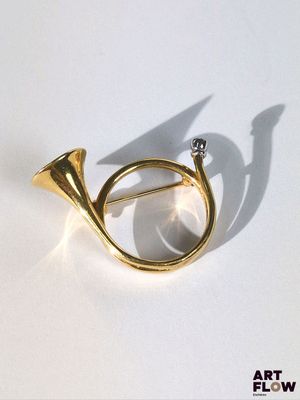 une broche en forme de corne en or, sertie d'un diamant