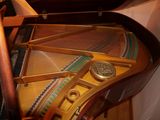 a close up of a grand piano with a clock on it