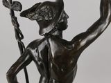bronze statue of a man holding a sword and a bird in his hand
