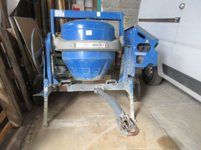 une bétonnière bleue garée dans un garage à côté d'une camionnette blanche