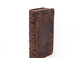 an old book with a brown cover sitting on top of a white surface
