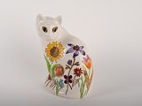 a white cat sitting on a white surface with flowers on it