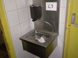 un lavabo dans un coin de la salle de bains, avec un distributeur de papier essuie-tout fixé au mur