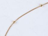 a close up of a gold plated necklace on a marble surface
