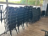 des rangées de chaises noires dans une pièce dotée de grandes fenêtres et d'un parquet