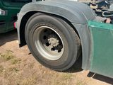 a green semi truck with a flat tire parked on the side of the road