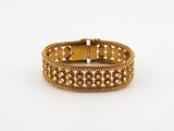 a close up of a gold bracelet on a white surface