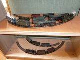 un circuit de train miniature posé sur une étagère en bois dans une pièce
