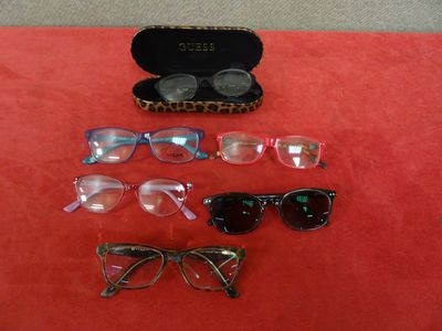 plusieurs paires de lunettes et un étui posés sur une surface rouge