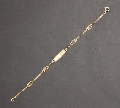 gros plan d'un bracelet en or sur une surface noire