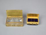 two gold boxes with blue glass in them on a table